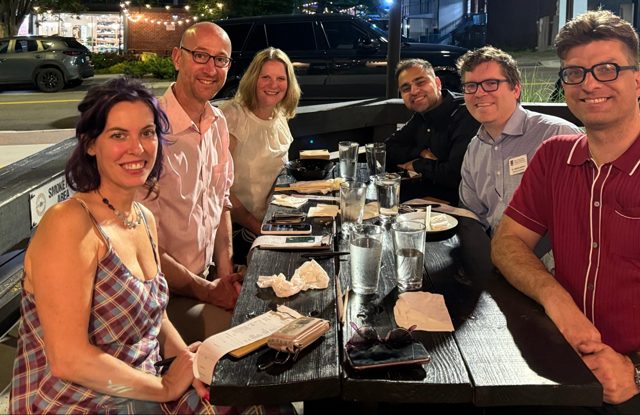 Six of us from the project around an outdoor table in Atlanta at night, smiling at the camera.